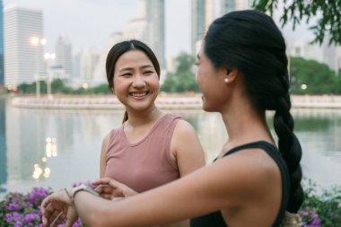 Güzel bir gün batımında Bangkok, Tayland 'da bir parkta spor yaptıktan sonra spor salonunda spor yapan iki gülümseyen bayan sporcu. spor konsepti