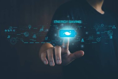 Enerji tasarrufu kavramı. Biri batarya koruyucu düğmesine basıyor. Sanal ekranda, enerji tasarrufu, küresel ısınmayı azaltma, çevreyi kurtarma, kirliliği azaltma, eko-teknoloji.
