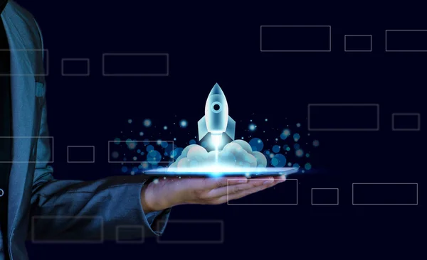 Startup business concept. Businessman holding a tablet, rocket launching and soar flying out from screen, starting a business, growing business, modern technology, hologram, network connection.