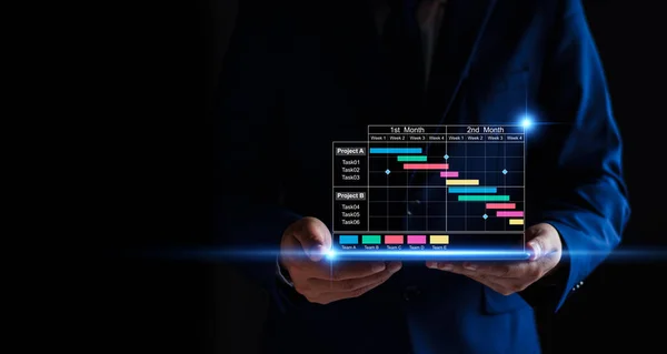 stock image Project manager working on tablet and updating tasks and milestones progress planning with Gantt chart scheduling interface for company on virtual screen. Business Project Management System.