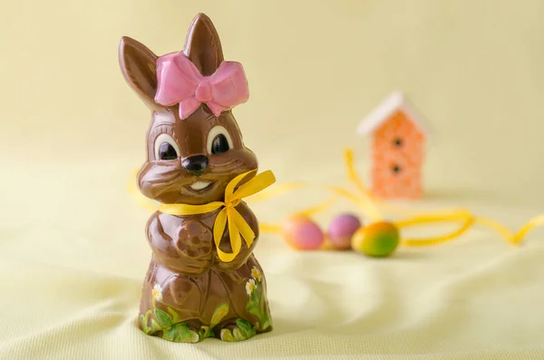 Çikolatalı tavşanın arka planında çikolata yumurtaları ve bir ev.