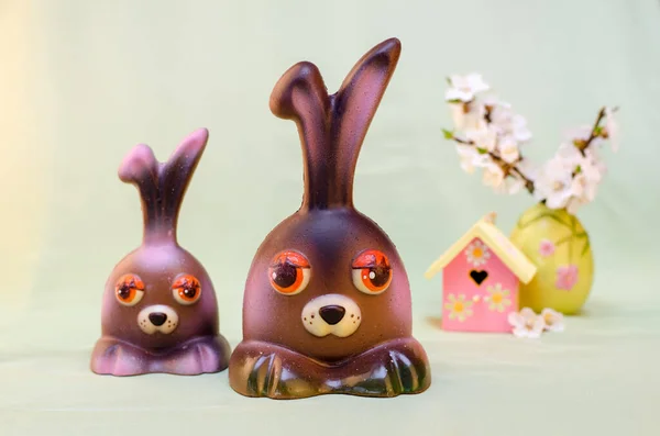 Hafif arka planda çikolatalı Paskalya tavşanları, 2 ev ve sakura.