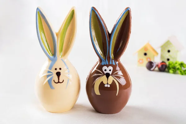 Beyaz arka planda çikolatalı Paskalya tavşanları ve iki ev