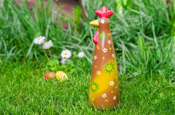 Çimenlerdeki çikolata horozu Papatya ve yumurtaların arka planında