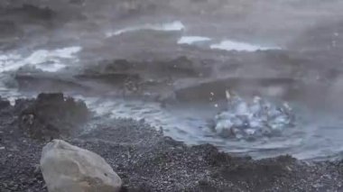 Laugarvatn, İzlanda 'daki jeotermal göl. Güçlü rüzgar, siyah çakıl taşlı sahil boyunca sıcak buhar üflerken jeotermal aktiviteden kaynayan zemine yaklaşın.