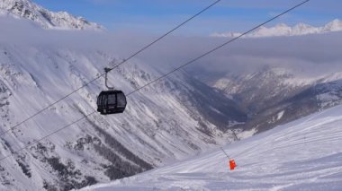 Obergurgl, Tyrol, Avusturya - 22 Ocak 2023: Avusturya 'nın Tyrol kentindeki Otztal Alpleri' nin kar kaplı dağlarının vadi manzarası. 60fps 'de çekilen, görüntünün ön cephesinde hareket eden teleferik arabaları var..