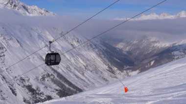 Obergurgl, Tyrol, Avusturya - 22 Ocak 2023: Avusturya 'nın Tyrol kentindeki Otztal Alpleri' nin kar kaplı dağlarının vadi manzarası. 60fps 'de çekilen, görüntünün ön cephesinde hareket eden teleferik arabaları var..