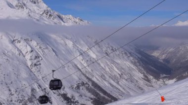 Obergurgl, Tyrol, Avusturya - 22 Ocak 2023: Avusturya 'nın Tyrol kentindeki Otztal Alpleri' nin kar kaplı dağlarının vadi manzarası. 60fps 'de çekilen, görüntünün ön cephesinde hareket eden teleferik arabaları var..