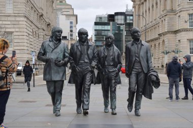 Liverpool, Merseyside, Birleşik Krallık - 12 Mart 2023: Liverpool 'un ikonik bronz heykeli The Beatles Heykeli listelenen Three Graces binalarının önündeki rıhtımın başındadır. Popüler Fab Four cazibesi