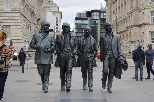 Liverpool, Merseyside, Birleşik Krallık - 12 Mart 2023: Liverpool 'un ikonik bronz heykeli The Beatles Heykeli listelenen Three Graces binalarının önündeki rıhtımın başındadır. Popüler Fab Four cazibesi