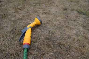 Bahçe hortumu kuru bir çimenlikte kullanılmadan duruyor. İngiltere 'de kuraklık nedeniyle yaz hortumu yasağı.