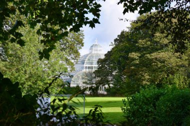 Liverpool, Merseyside, United Kingdom: The Palm house peaking out behind green trees in Sefton Park, Liverpool clipart