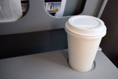 Gri katlanabilir uçak tepsisi üzerinde sade, tek kullanımlık kahve fincanı..