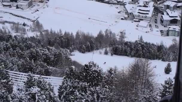 上から雪が降るオーストリアのスキー場とスキー場 上昇スキーリフトから撮影された雪の村と冬のスポーツの斜面の空中ビュー — ストック動画