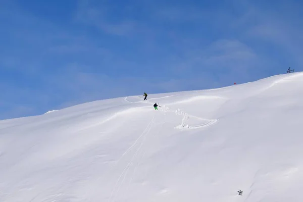 Pair of off-piste skiers climbing back up after a wrong turn whilst backcountry skiing in the Austrian alps.