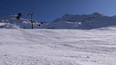 Aktif kayakçılar ve snowboardcular güneşli bir günde dağ yamacına iniyorlar. Avusturya Alplerinde yer alan Hochgurgl kayak merkezinde sessiz kayak yamacı.