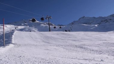 Kayakçılar ve snowboardcular güneşli bir günde dağ yamacına iniyorlar. Avusturya Alplerinde yer alan Hochgurgl kayak merkezinde aktif kayak yamacı.