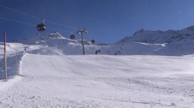 Aktif kayakçılar ve snowboardcular güneşli bir günde dağ yamacına iniyorlar. Avusturya Alplerinde yer alan Hochgurgl kayak merkezinde sessiz kayak yamacı.
