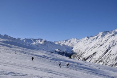 Hochgurgl kayak merkezindeki kayakçılar ve snowboardcular, Otztal Vadisi 'nin ve Avusturya' nın Tyrol kentindeki kar kaplı dağların arkasında güneşli bir günde, kış sporları için mükemmel koşullar..