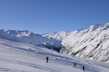 Hochgurgl kayak merkezindeki kayakçılar ve snowboardcular, Otztal Vadisi 'nin ve Avusturya' nın Tyrol kentindeki kar kaplı dağların arkasında güneşli bir günde, kış sporları için mükemmel koşullar..