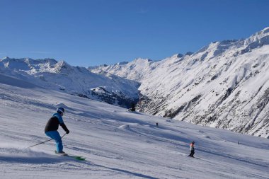 Hochgurgl kayak merkezindeki kayakçılar ve snowboardcular, Otztal Vadisi 'nin ve Avusturya' nın Tyrol kentindeki kar kaplı dağların arkasında güneşli bir günde, kış sporları için mükemmel koşullar..