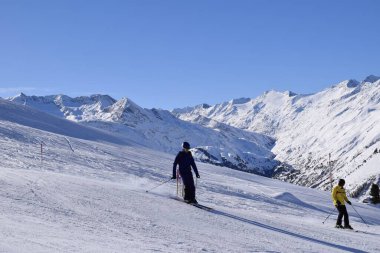 Hochgurgl kayak merkezindeki kayakçılar ve snowboardcular, Otztal Vadisi 'nin ve Avusturya' nın Tyrol kentindeki kar kaplı dağların arkasında güneşli bir günde, kış sporları için mükemmel koşullar..