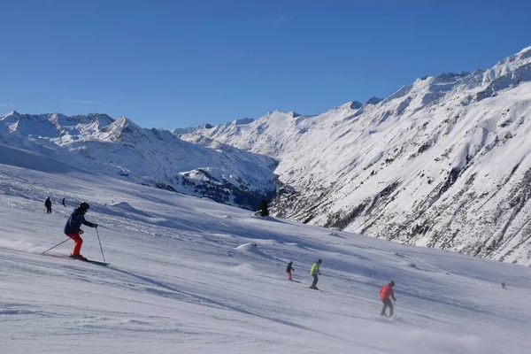 Hochgurgl kayak merkezindeki kayakçılar ve snowboardcular, Otztal Vadisi 'nin ve Avusturya' nın Tyrol kentindeki kar kaplı dağların arkasında güneşli bir günde, kış sporları için mükemmel koşullar..