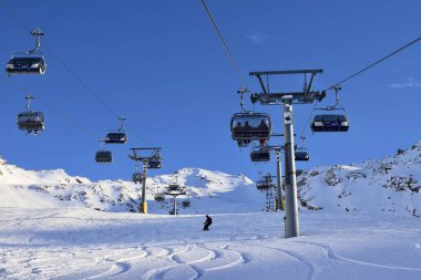 Hochgurgl, Tyrol, Avusturya - 25 Ocak 2023: Avusturya kayak merkezinde sandalye kaldırma. Güneşli bir kış gününde kayakçılar ve snowboardcular için üstten kaldırma, karlı dağlar ve kayak yamaçları..