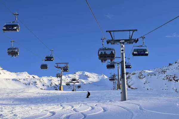 Hochgurgl, Tyrol, Avusturya - 25 Ocak 2023: Avusturya kayak merkezinde sandalye kaldırma. Güneşli bir kış gününde kayakçılar ve snowboardcular için üstten kaldırma, karlı dağlar ve kayak yamaçları..