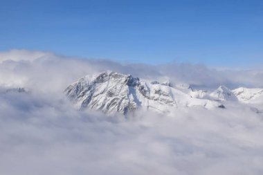 Ağır bulutların arasından yükselen dağlık dağ sırasının nefes kesen hava manzarası. Yukarıdan Otztal Alpleri 'nin dağ zirveleri. Etkileyici kış manzarası bir uçak penceresinden alınır..