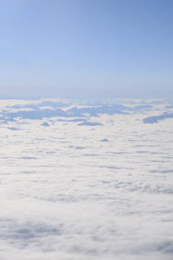Ağır bulutların arasından yükselen dağ tepeli dağların rüya gibi hava manzarası. Yukarıdan Otztal Alpleri 'nin uzak dağ zirveleri. Etkileyici görüntü uçarken bir uçak penceresinden alınır..