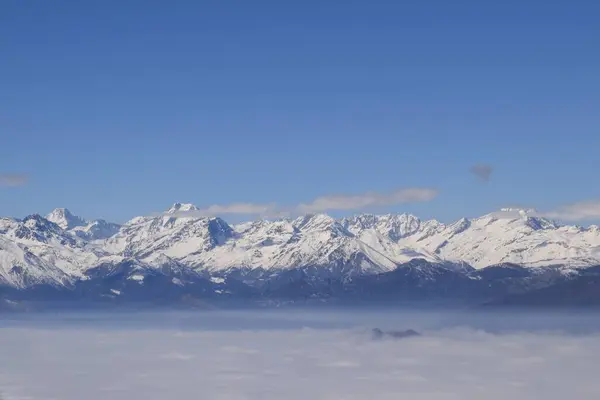 Karla kaplı dağ sırasının güzel hava manzarası ağır bulutların arasından yükseliyor. Yukarıdan, İtalyan Alpleri 'nin dağ zirveleri. Etkileyici kış manzarası bir uçak penceresinden alınır..