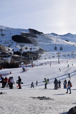 Les Menuires - March 11 2024: Skiers gathering at the Base Area of Les Menuires Ski Resort in the morning for a beautiful day of skiing and snowboarding in the Three Valleys, French Alpine mountains. clipart