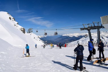 Meribel, France - March 13 2024: Skiers and snowboarders at the top of Meribel ski resort in France with overhead gondolas. View from the peak of Mont Vallon overlooking the breathtaking Three Valleys clipart