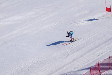 Les Menuires, Fransa - 14 Mart 2024: Aksiyon yarışı slalom kayağı sporcuları yüksek hızlarda dönüyor. Les Menuires kayak merkezindeki kayak pistlerinde performans sergileyen gelişmiş kayakçılar. Koltuk asansöründen görünüm.