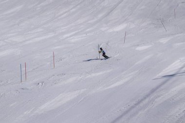 Les Menuires, Fransa - 14 Mart 2024: Aksiyon yarışı slalom kayağı sporcuları yüksek hızlarda dönüyor. Les Menuires kayak merkezindeki kayak pistlerinde performans sergileyen gelişmiş kayakçılar. Koltuk asansöründen görünüm.