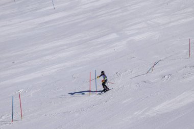 Les Menuires, Fransa - 14 Mart 2024: Aksiyon yarışı slalom kayağı sporcuları yüksek hızlarda dönüyor. Les Menuires kayak merkezindeki kayak pistlerinde performans sergileyen gelişmiş kayakçılar. Koltuk asansöründen görünüm.