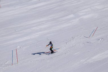 Les Menuires, Fransa - 14 Mart 2024: Aksiyon yarışı slalom kayağı sporcuları yüksek hızlarda dönüyor. Les Menuires kayak merkezindeki kayak pistlerinde performans sergileyen gelişmiş kayakçılar. Koltuk asansöründen görünüm.