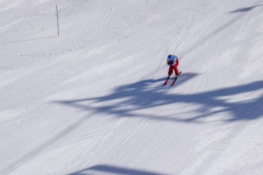 Les Menuires, France - March 14 2024: Athletes in action racing slalom ski turns at high speeds. Advanced skiers performing on ski slopes in Les Menuires ski resort. View from an overhead chair lift. clipart