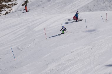 Les Menuires, Fransa - 14 Mart 2024: Aksiyon yarışı slalom kayağı sporcuları yüksek hızlarda dönüyor. Les Menuires kayak merkezindeki kayak pistlerinde performans sergileyen gelişmiş kayakçılar. Koltuk asansöründen görünüm.