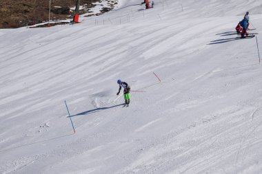 Les Menuires, Fransa - 14 Mart 2024: Aksiyon yarışı slalom kayağı sporcuları yüksek hızlarda dönüyor. Les Menuires kayak merkezindeki kayak pistlerinde performans sergileyen gelişmiş kayakçılar. Koltuk asansöründen görünüm.