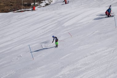 Les Menuires, France - March 14 2024: Athletes in action racing slalom ski turns at high speeds. Advanced skiers performing on ski slopes in Les Menuires ski resort. View from an overhead chair lift. clipart