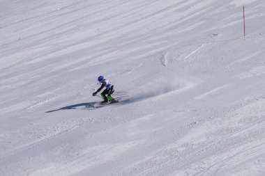 Les Menuires, Fransa - 14 Mart 2024: Aksiyon yarışı slalom kayağı sporcuları yüksek hızlarda dönüyor. Les Menuires kayak merkezindeki kayak pistlerinde performans sergileyen gelişmiş kayakçılar. Koltuk asansöründen görünüm.