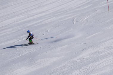 Les Menuires, Fransa - 14 Mart 2024: Aksiyon yarışı slalom kayağı sporcuları yüksek hızlarda dönüyor. Les Menuires kayak merkezindeki kayak pistlerinde performans sergileyen gelişmiş kayakçılar. Koltuk asansöründen görünüm.