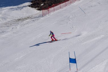 Les Menuires, Fransa - 14 Mart 2024: Aksiyon yarışı slalom kayağı sporcuları yüksek hızlarda dönüyor. Les Menuires kayak merkezindeki kayak pistlerinde performans sergileyen gelişmiş kayakçılar. Koltuk asansöründen görünüm.