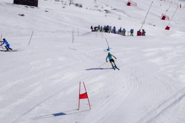 Les Menuires, Fransa - 14 Mart 2024: Aksiyon yarışı slalom kayağı sporcuları yüksek hızlarda dönüyor. Les Menuires kayak merkezindeki kayak pistlerinde performans sergileyen gelişmiş kayakçılar. Koltuk asansöründen görünüm.