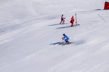 Les Menuires, Fransa - 14 Mart 2024: Aksiyon yarışı slalom kayağı sporcuları yüksek hızlarda dönüyor. Les Menuires kayak merkezindeki kayak pistlerinde performans sergileyen gelişmiş kayakçılar. Koltuk asansöründen görünüm.