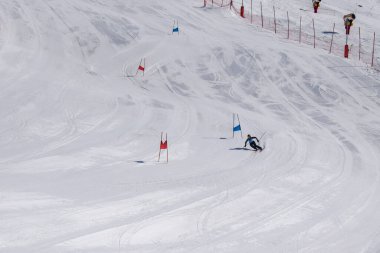 Les Menuires, Fransa - 14 Mart 2024: Aksiyon yarışı slalom kayağı sporcuları yüksek hızlarda dönüyor. Les Menuires kayak merkezindeki kayak pistlerinde performans sergileyen gelişmiş kayakçılar. Koltuk asansöründen görünüm.