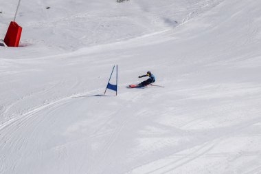 Les Menuires, Fransa - 14 Mart 2024: Aksiyon yarışı slalom kayağı sporcuları yüksek hızlarda dönüyor. Les Menuires kayak merkezindeki kayak pistlerinde performans sergileyen gelişmiş kayakçılar. Koltuk asansöründen görünüm.