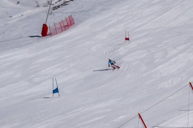 Les Menuires, Fransa - 14 Mart 2024: Aksiyon yarışı slalom kayağı sporcuları yüksek hızlarda dönüyor. Les Menuires kayak merkezindeki kayak pistlerinde performans sergileyen gelişmiş kayakçılar. Koltuk asansöründen görünüm.